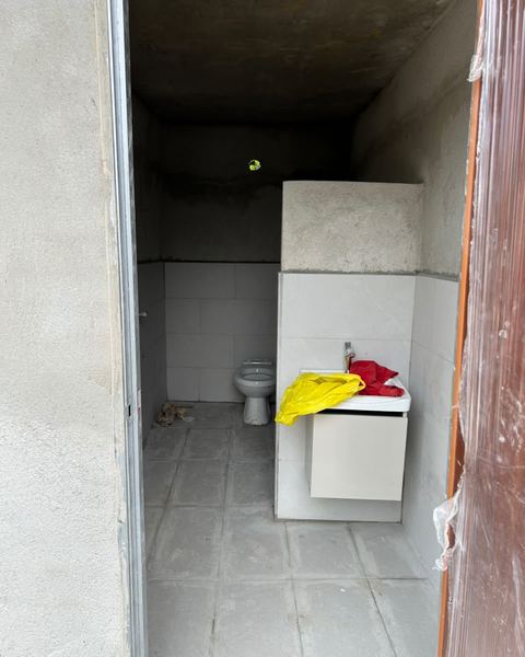 Bilik mandi yang hampir siap, dengan lantai jubin, tandas dan sinki
