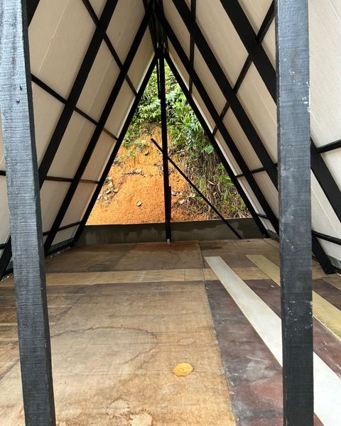 Di dalam sebuah A-frame yang belum siap, memandang keluar ke arah pokok